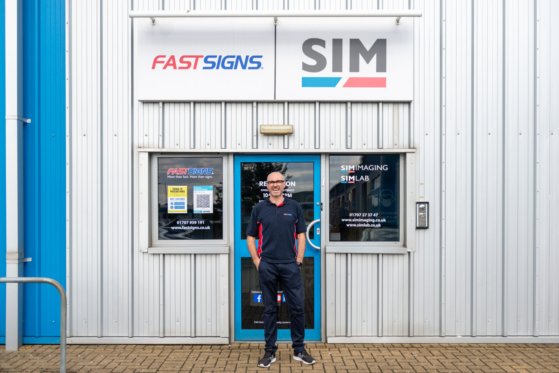 Lee Simpson stands outside his Cobrand centre under FASTSIGNS and SIM signage